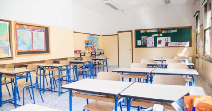 una aula di scuola con banchi lavagna e sedie